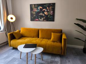 a living room with a yellow couch and a table at maremar - Apartments am Ferberturm - Luxus Boxspringbett - Küche - Arbeitsplatz - WLAN in Gera