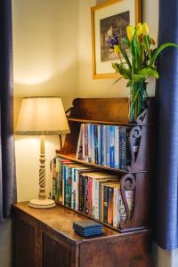 a book shelf full of books with a lamp and a vase of flowers at Castle Cottage No 2 in Acharn