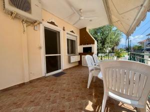 a balcony with white chairs and a table and a kitchen at Casa d'Angelo by Horizon Homes in Orfánion +3 photos