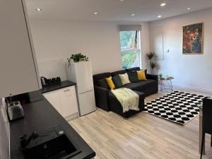 a living room with a black couch and a kitchen at Family & Contractor Haven Suites Mexborough in Mexborough