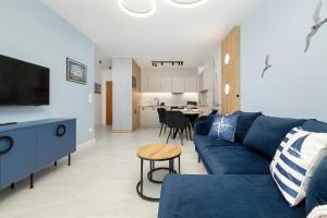 een woonkamer met een blauwe bank en een tafel bij Apartamenty Baltic Marina in Międzywodzie