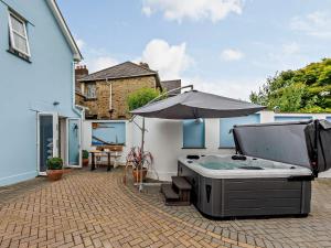 a patio with a hot tub and an umbrella at 4 Bed in Combe Martin 83502 in Combe Martin