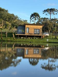 a house with a reflection in the water at Cabana do Lago com passeios a cavalo gratuito in Urubici