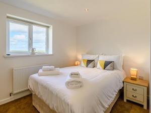 a bedroom with a large white bed with two towels on it at 3 bed in Bamburgh 79178 in Belford