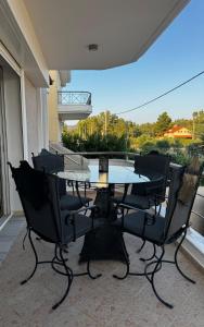 a glass table and chairs on a balcony at Vei Estate in Schinias