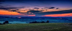 a field with a sunset in the background with a sky at Karavan na samotě u lesa in Zámrsky