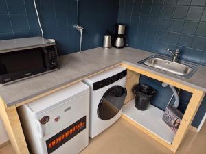 a kitchen with a sink and a washing machine at NATO bunker with nice bed and appliancies in Mikkeli +7 photos