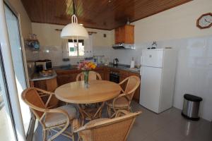 cocina con mesa de madera y nevera blanca en Casa Daniela en Calheta