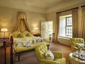 ein Schlafzimmer mit einem Bett, einer Couch und einem Stuhl in der Unterkunft Llangoed Hall in Bronllys