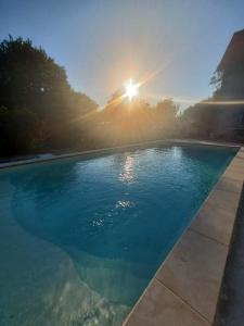 a large swimming pool with the sun in the background at Domaine de l'Atrée - Tente Maasaï Poyaudine in Saint-Martin-des-Champs +14 photos