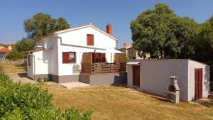a small white house with a fence in a yard at House Meli in Rakalj