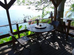 a table and chairs on a deck with the ocean at Les Portes du Paradis, surplombant la mer in Pointe-Noire
