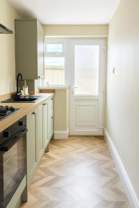 a kitchen with white cabinets and a window at Renas Seahaven Cottage in Cullercoats