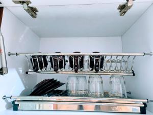 ein Regal in einer Küche mit Gläsern und Utensilien in der Unterkunft Nita's Sweet Apartment Gunawangsa Manyar 2BR - close to Unair Galaxy Mall in Surabaya