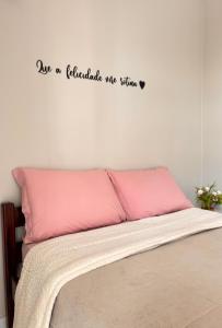 a bedroom with a bed with a pink pillow at Suítes da Orla Hospedagens in Arraial do Cabo