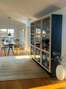 a kitchen and dining room with a large glass cabinet at Architect-Designed House With Private Beach in Løgstrup +25 photos