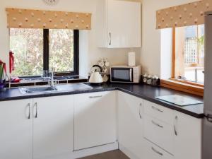 eine Küche mit weißen Schränken und einer Spüle und einem Fenster in der Unterkunft Heyope Cottage in Llangunllo