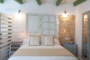 1 dormitorio con 1 cama grande y pared de piedra en Alhanía Vejer, en Vejer de la Frontera