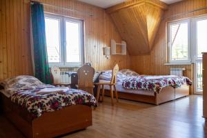two beds in a room with wooden walls and windows at Pokoje Gościnne Janina in Zakopane