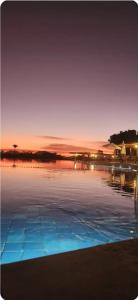 a pool of water with a sunset in the background at Apto 1qto Quinta Santa Bárbara in Pirenópolis