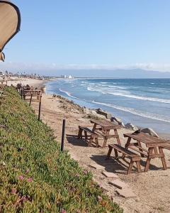 a row of wooden picnic tables on a beach at Punta Playa 2 bedroom house in Ensenada