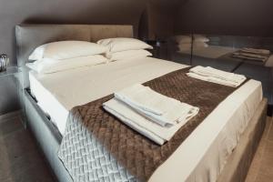 Una cama grande con sábanas blancas y toallas. en Cattedrale Suite, en Palermo