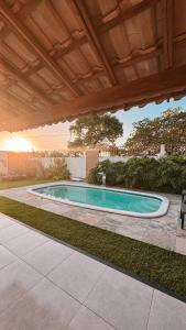 a swimming pool in a yard with a wooden roof at Lençóis Maranhenses - Casa Armonia in Santo Amaro