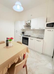 una cucina con armadi bianchi e un tavolo con fiori di Home Sisters a Trapani