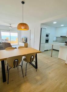 Una cocina y un comedor con mesa y sillas de madera. en Delícies Mar apartamento, en Sant Carles de la Ràpita