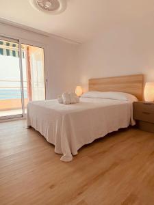 Un dormitorio blanco con una cama y una ventana grande. en Delícies Mar apartamento, en Sant Carles de la Ràpita