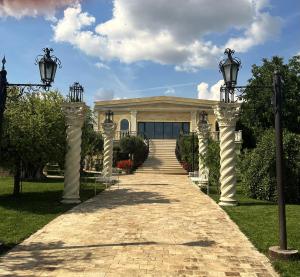 a walkway leading to a building with columns and lights at Hotel Malvina in Sînnicolau Mare +33 photos