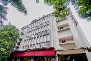 a tall white building with a red awning at Collection O MG Guest House in Kolkata