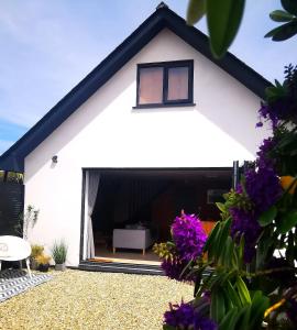 a white house with a window and purple flowers at Gwynn Lodge in Newquay +19 photos