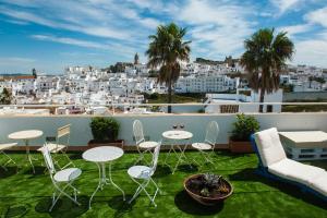a balcony with tables and chairs and a view of the city at Alhanía Vejer in Vejer de la Frontera