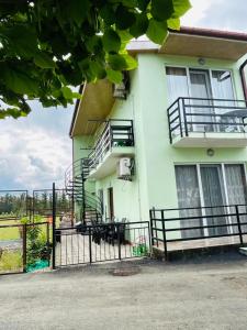 a building with stairs and a fence in front of it at Green Cottage in Ureki