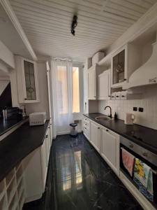 a kitchen with white cabinets and black counter tops at Menton centre Cosy and spacious in Menton