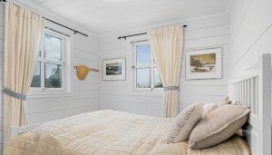a white bedroom with a bed and two windows at Peaceful Cabin In Skrabbavikjå With Fjord View in Hervik