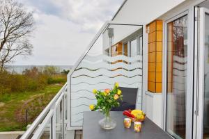 een balkon met een vaas met bloemen op een tafel bij Ferienwohnung Meeresblick in Juliusruh