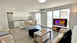 ein Wohnzimmer mit einer Couch, einem Fernseher und einem Tisch in der Unterkunft ROMPEOLAS GANDIA - Alquiler solo a familias in Gandía