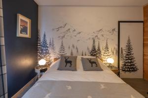 une chambre avec un lit avec deux oreillers et une fresque de montagne dans l'établissement Chaleureuse Fruitière – 8 personnes, à Samoëns