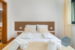 a bedroom with a white bed with towels on it at Lagar da Vila - Dream Lodging in Avelar