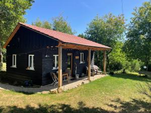 a small black cabin with a red roof at Gite La Chouette met hottub in Beyssac