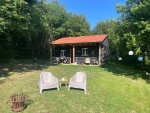 two chairs and a table in front of a cabin at Gite La Chouette met hottub in Beyssac