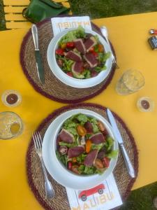 zwei Teller Essen auf einem Tisch mit Salat in der Unterkunft Les ambiances du Coly, La chambre Vézère in Condat-sur-Vézère + 16 Fotos
