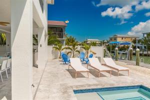 a patio with chairs and a swimming pool at Casa Del Mar- Luxury Waterfront Pool Home, 45' Dock in Marathon