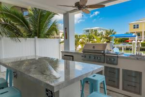 a outdoor kitchen with a grill and blue stools at Casa Del Mar- Luxury Waterfront Pool Home, 45' Dock in Marathon