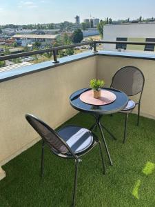 a patio table and two chairs on a balcony at Apartman NS FREE PARKING in Novi Sad