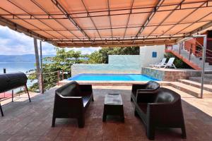 a patio with two chairs and a swimming pool at Quinta Sunrise, Lago de Coatepeque in El Congo