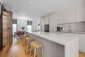 a kitchen with white cabinets and bar stools at Stunning Luxury Townhouse in Centre of Manchester in Manchester