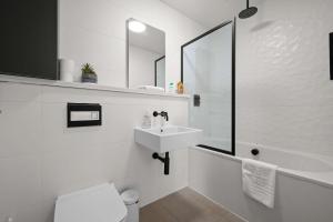 a white bathroom with a sink and a bath tub at Stunning Luxury Townhouse in Centre of Manchester in Manchester